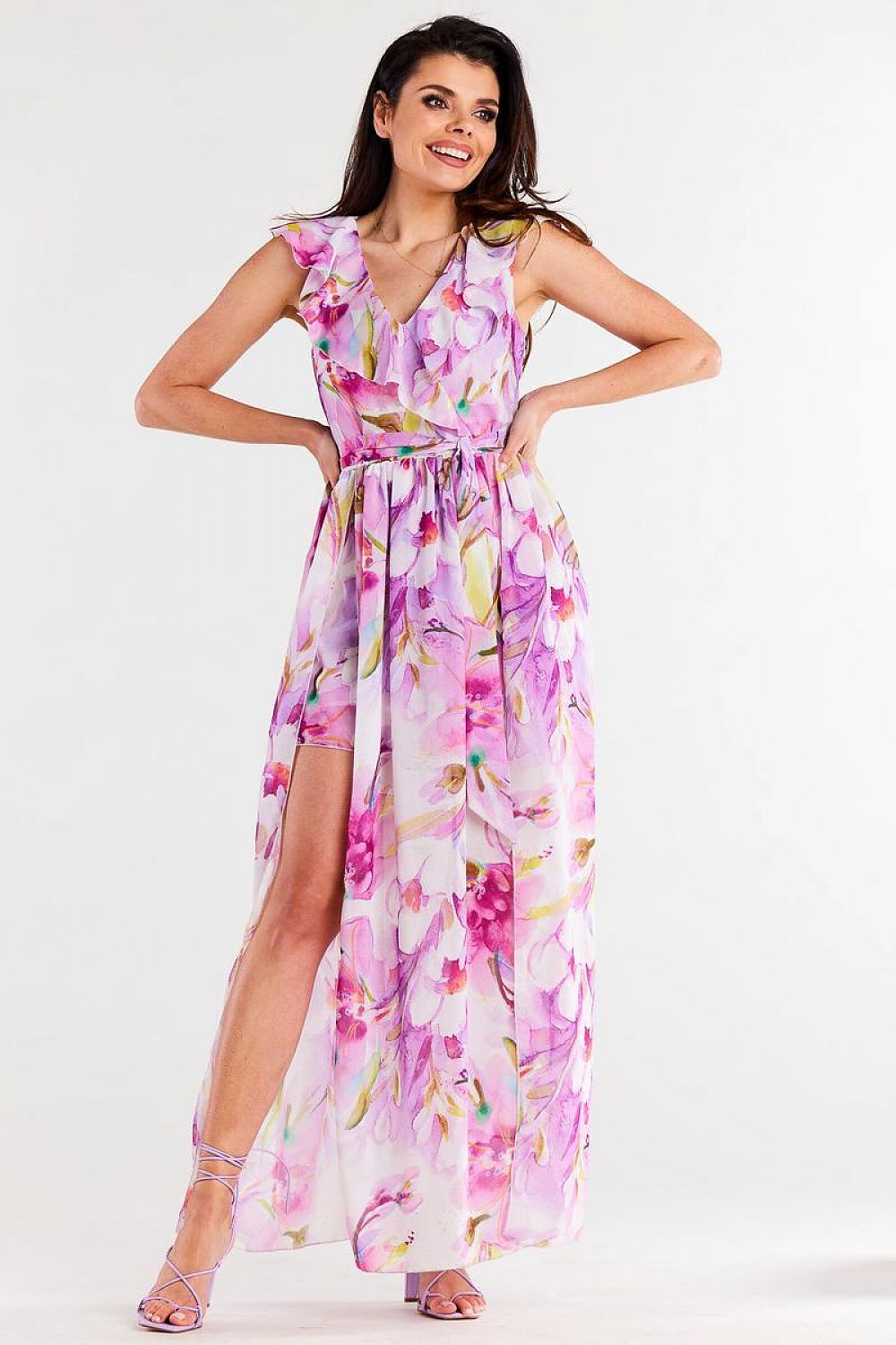 Vrouw draagt Flair Élan asymmetrische chiffonjurk met ruche, ceintuur en elegante splitten.