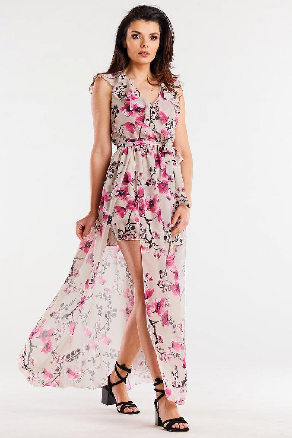 Vrouw draagt Flair Élan asymmetrische chiffonjurk met ruche, ceintuur en elegante splitten.
