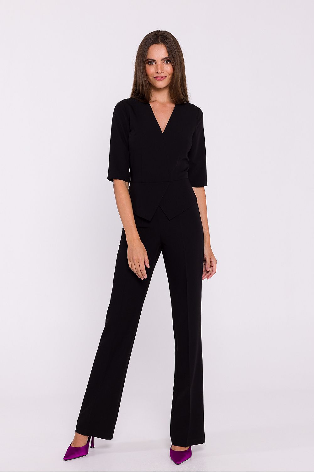 Vrouw draagt Viva Élégance jumpsuit met V-hals en wijde pijpen – chique dames jumpsuit met elegante pasvorm en vrouwelijke uitstraling.