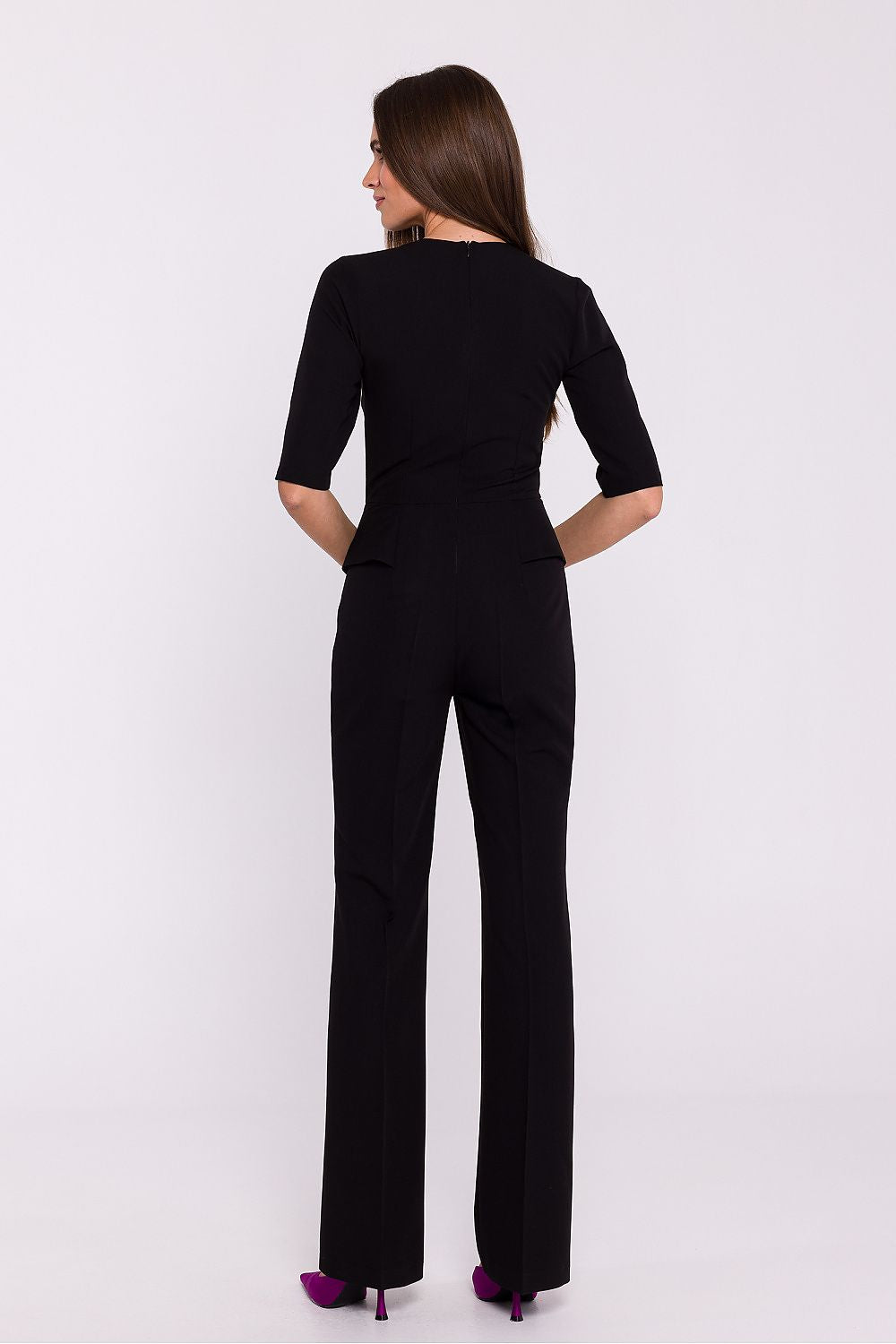 Vrouw draagt Viva Élégance jumpsuit met V-hals en wijde pijpen – chique dames jumpsuit met elegante pasvorm en vrouwelijke uitstraling.