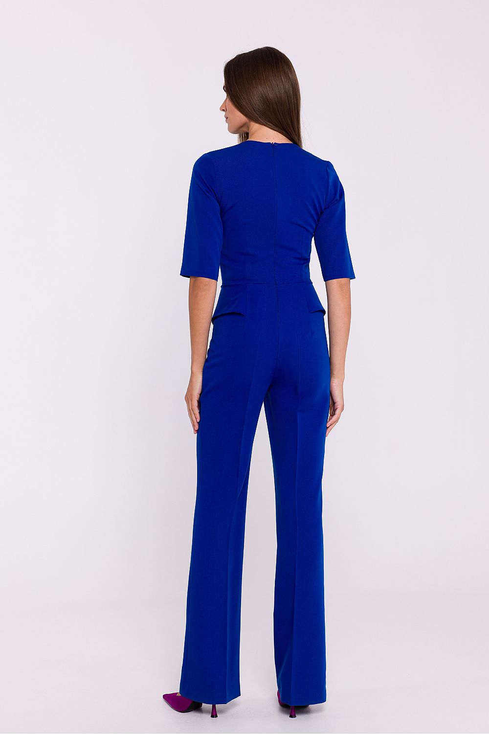 Vrouw draagt Viva Élégance jumpsuit met V-hals en wijde pijpen – chique dames jumpsuit met elegante pasvorm en vrouwelijke uitstraling.