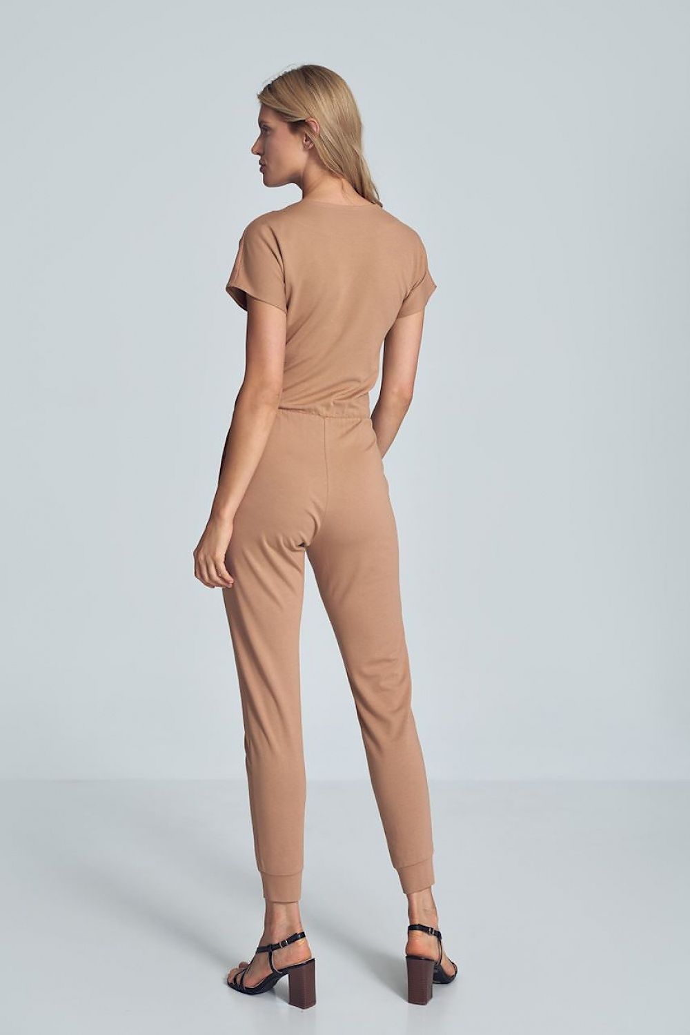 Beige jumpsuit met crinkle halslijn, elastische taille en taps toelopende pijpen met drawstring.