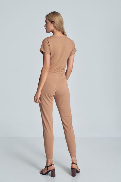 Beige jumpsuit met crinkle halslijn, elastische taille en taps toelopende pijpen met drawstring.